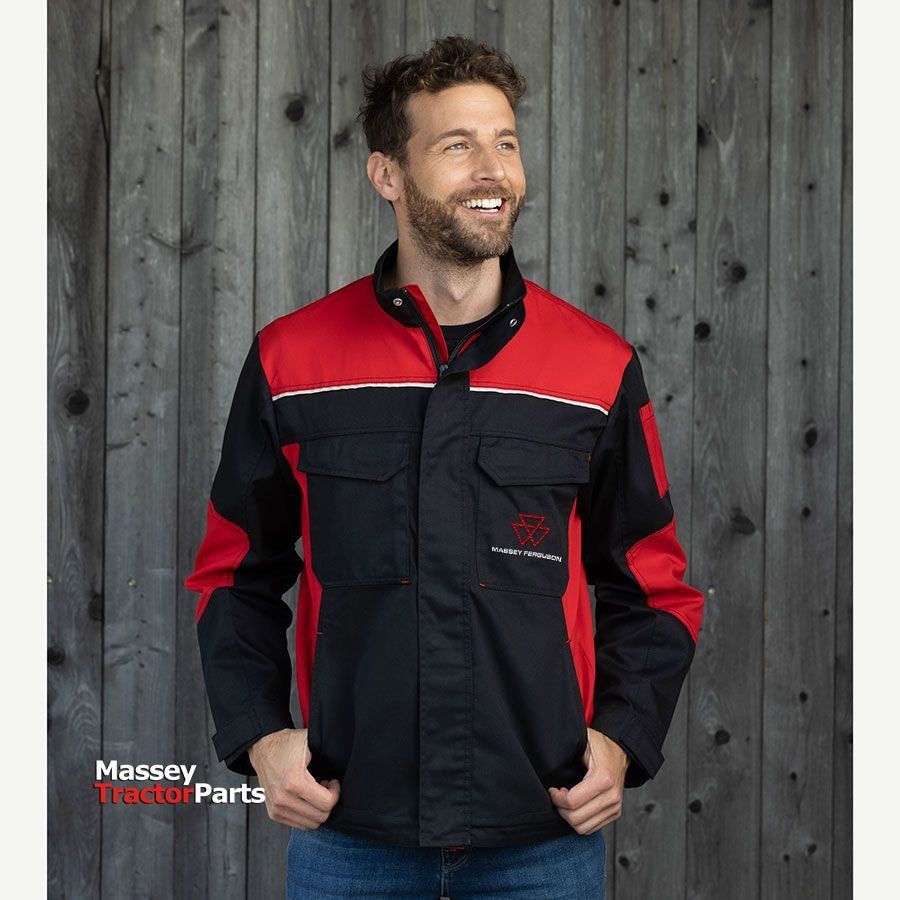 A man in a durable AGCO work jacket branded with "Massey Ferguson" poses in front of a wooden wall. The black and red polyester-cotton jacket, model X993452201, features reflective details for added safety.
