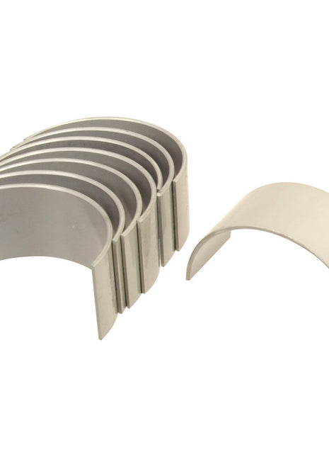 The Sparex Conrod Bearing +0.030'' (0.75mm) Set | Sparex Part No.S.111794 includes a set of seven silver-colored semi-circular metal bearings, with six stacked together and one separated in front, ideal for use with Massey Ferguson tractors.