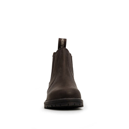 A single Xpert Heritage Wrangler Junior Dealer Boot in dark brown, from the brand Cottonmount, photographed from the front against a white background. The boot features a black tag with the text "HERIT" visible at the top and boasts a cushioned footbed for added comfort.