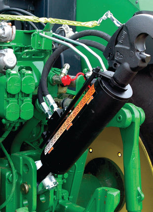 Close-up of a Sparex Hydraulic Top Link (Cat.28mm/3) Knuckle and Q.R CBM Hook, connected to a green agricultural machine, showcasing various pipes, valves, and components. This versatile tractor implement features a robust 90mm cylinder bore for efficient performance in the field with a minimum length of 650mm (Sparex Part No. S.331203).