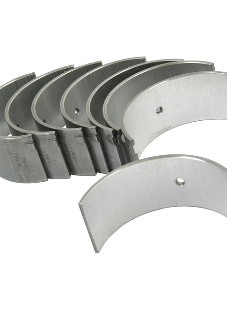 A set of six silver Conrod Bearing +0.010'' (0.25mm) Set | Sparex Part No.S.42499, arranged in a semi-circular formation on a white background, perfect for Massey Ferguson or Landini machinery from Sparex.