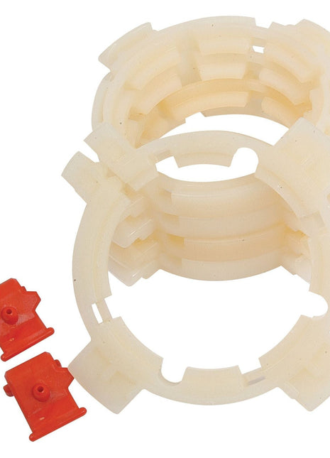 Image of four stacked, circular, beige plastic rings with notches and two small red plastic clips positioned beside them. This resembles the EASYLOCK BEARING PACK - LARGE from Sparex (Part No. S.20537), featuring large components for secure assembly.