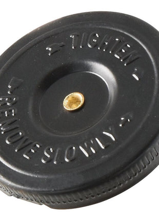 A circular black plastic Sparex Fuel Cap With Lock - S.65002, with the instructions "TIGHTEN" and "REMOVE SLOWLY" in raised letters, featuring a small brass-colored center point.
