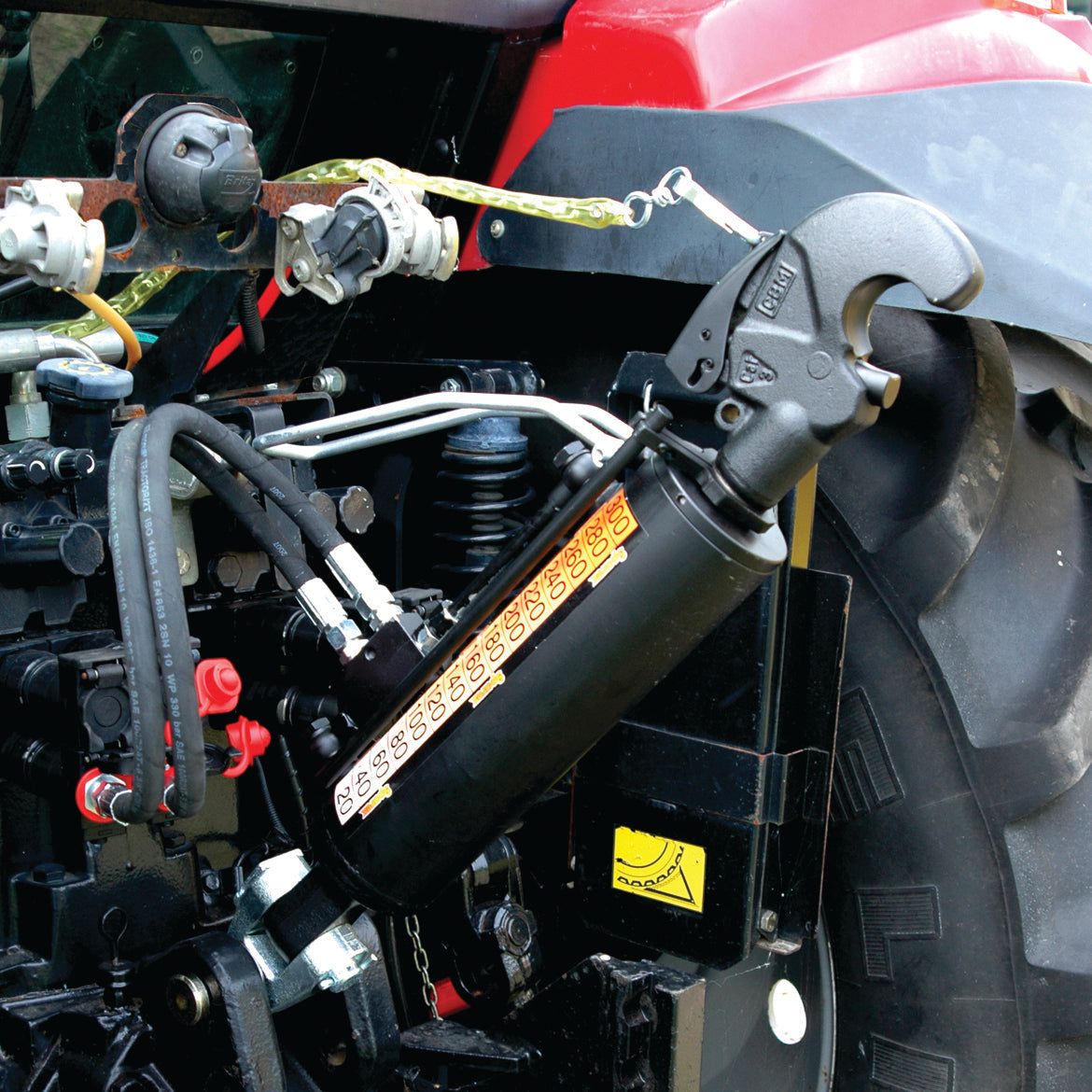Close-up of the Sparex Hydraulic Top Link (Cat. 2/3) Knuckle and Q.R CBM Hook, Cylinder Bore: 90mm, showcasing connected mechanisms and hoses on agricultural machinery. The red and black color scheme complements the tractor seamlessly.