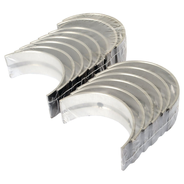 Two stacks of Sparex metal bearing shells (Main Bearing +0.020'' (0.50mm) Set | Sparex Part No.S.60337), suitable for Landini, arranged in a slightly curved, overlapping pattern, isolated on a white background.