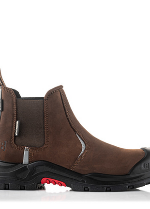 The Buckler Nubuckz Safety Dealer Boot (Nkz101Br) is a brown leather slip-on work boot featuring a black slip-resistant rubber sole and toe cap with red accents. This piece of safety footwear from Buckler ensures both durability and style.