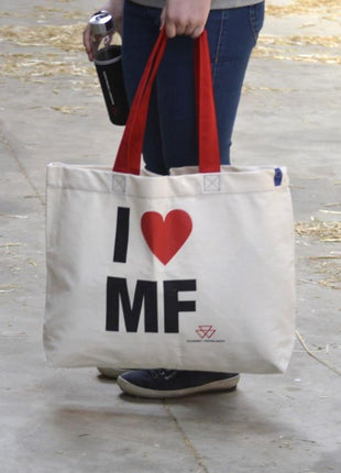 Person holding an AGCO Massey Ferguson shopping bag (Product Code: X993342304000) made of beige cotton with red handles and the text "I ♥ MF" printed on it, while carrying a black drink container.