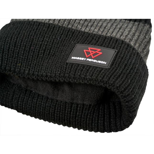 Close-up of the AGCO Massey Ferguson knitted beanie (X993482302000), featuring a black and grey woolen design with an embroidered red logo and "Massey Ferguson" text on a black patch.