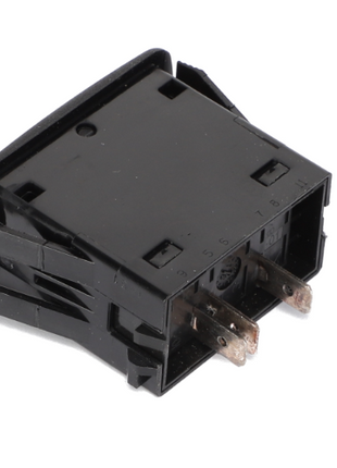 Close-up of an AGCO ROCKER SWITCH - AG124432, a black plastic electrical component featuring metal prongs. The switch is viewed from an angle that clearly shows its connectors. This rocker switch is branded by AGCO.