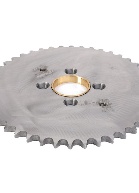 The AGCO Gear Cutting Table Drive Transmission - La300115357 is a silver metal sprocket with evenly spaced teeth around the edge, featuring a central golden bushing and four smaller holes surrounding the center. This genuine AGCO Parts component ensures your machinery runs smoothly and efficiently.