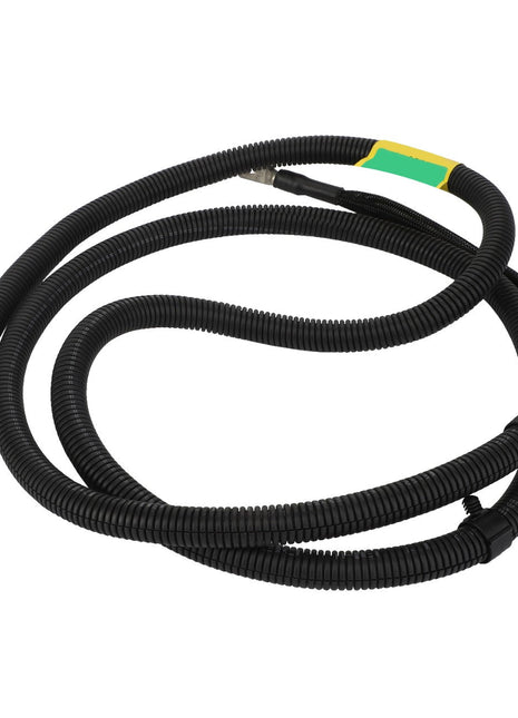 The AGCO Supply Cable - Acw6046400 is a coiled black electrical cable featuring a green and yellow label, and it includes a metal connector on one end.
