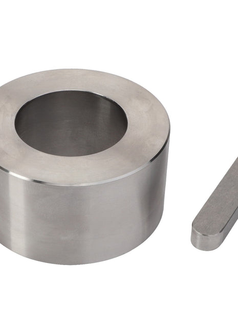 The AGCO | Kit - Acx3033090, produced by AGCO, consists of a polished cylindrical metal object with a large central hole and an accompanying smaller, oval-shaped metal piece positioned to the right; however, no additional product description is available at this time.