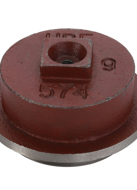 The AGCO Cap - Acp0209090 is a red metal tool with a circular base, featuring a square hole in the center and marked with the number "574" along with other stampings.