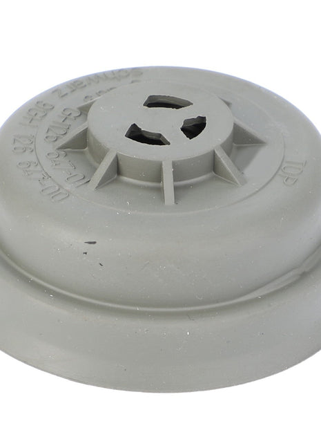 The AGCO CAP - F716900020030 is a grey plastic cap with text and symbols, designed for Massey Ferguson tractor models, featuring a circular shape, raised center section, and four side openings.