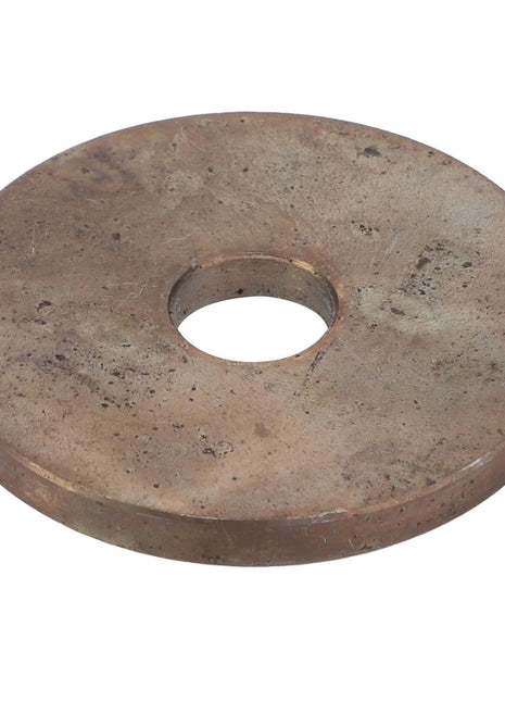 The AGCO | Washer - Acw1701240 is a large, flat, round metal washer with a central hole. The surface appears worn and tarnished.