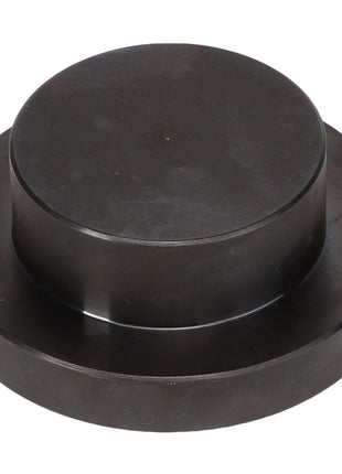 The AGCO Seal Kit - Acp0437710 is a round, black metallic disc featuring a raised circular section in the center, resembling a large button or cap.