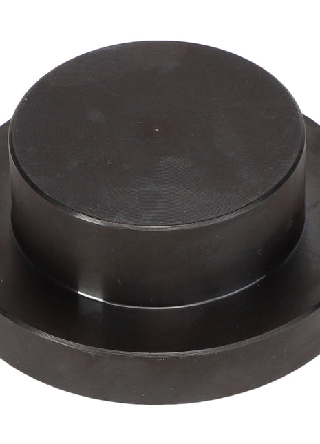 The AGCO Seal Kit - Acp0437710 is a round, black metallic disc featuring a raised circular section in the center, resembling a large button or cap.