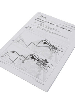 The manual titled "AGCO | Fit.Instruction - Act001375B" is laid flat and open to a page featuring diagrams and text on fitting the Power Beyond Kit to a CVT Tractor. The cover currently lacks a product description.