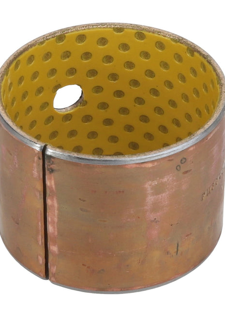 The AGCO BUSH - AL5018909 is a cylindrical metal bushing with a yellow perforated interior, featuring a distinct seam on its outer surface and a single hole.