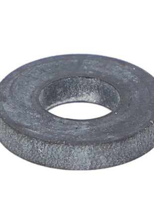 A close-up image of the AGCO Gasket - Ag006063, a dark, flat, round metal washer with a central hole, commonly used in engineering and construction.