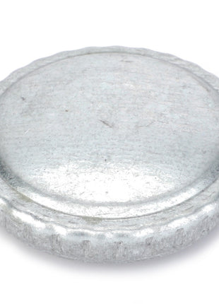 A close-up view of a slightly tarnished AGCO Oil Fill Cap (F291200310461) with small ridges around the edge, ensuring secure sealing against contaminants.