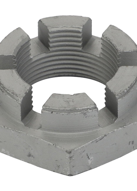 Close-up of an AGCO | Nut - Acw0433070, a metal castellated nut with grooves used in mechanical applications to prevent loosening. The hexagonal-shaped nut features a cylindrical hole in the center. No current product description information available.