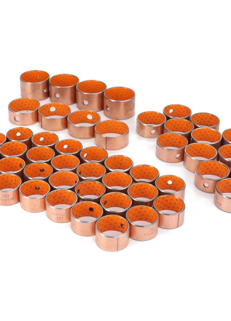 A collection of AGCO metal cylindrical bushings, model AL5018913, accented with vibrant orange interiors, meticulously arranged in neat rows on a pristine white surface.