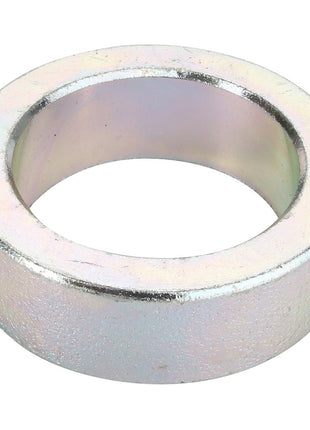 The AGCO Spacer - Acw0416410, a metallic, cylindrical washer with a hollow center, gleams as light reflects off its smooth surface.