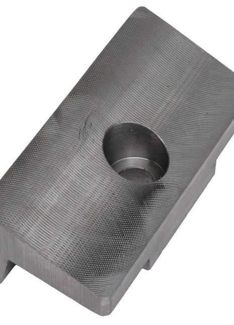 The AGCO | Angle Bale Stop - Acx2873610 by AGCO is a durable metal block featuring a textured surface and a central cylindrical indentation, providing both durability and functionality.