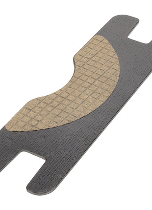 Close-up of the AGCO Brake Pad - Acp0483330, a rectangular, dark gray plastic object with a textured beige area and notches on both ends.