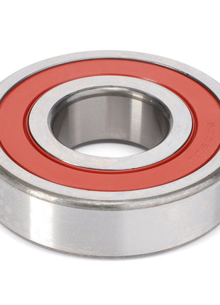 A close-up image of the AGCO Ball Bearing - F934201040100 with a red rubber seal in the middle, designed to handle radial and axial loads while minimizing rotational friction, surrounded by metal.