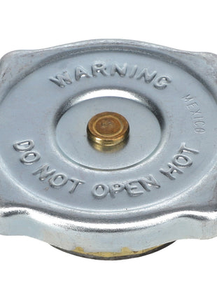 The AGCO | RADIATOR CAP - AG724582 is a metallic AGCO Genuine Radiator Cap with raised lettering that reads "WARNING MEXICO DO NOT OPEN HOT" on the top, designed to maintain cooling system pressure and prevent coolant boiling.