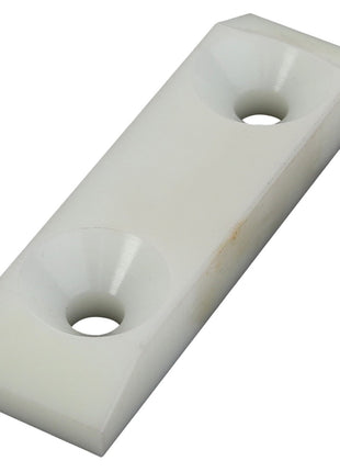 The AGCO | Strip Trim - Lm04105306 from the brand AGCO features a rectangular plastic spacer with two countersunk holes, beveled corners, and a slightly angular surface, compatible with Fendt models.