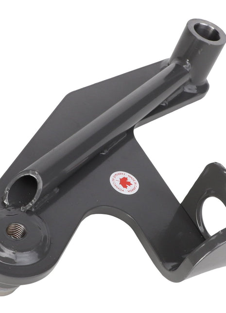 The AGCO | Idler Arm - Acw550859A is a gray metal bracket featuring three distinct attachment points, including a pivot bracket and a cylindrical section. A sticker with a red maple leaf is visible on its surface. No current product description information is available from AGCO.