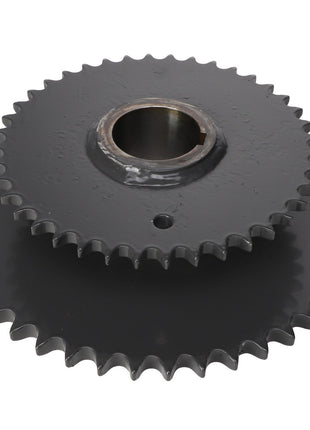 Two AGCO Sprocket - Acx2432710 gears, featuring interlocking teeth, are stacked on top of each other, showcasing their circular shape and central holes.