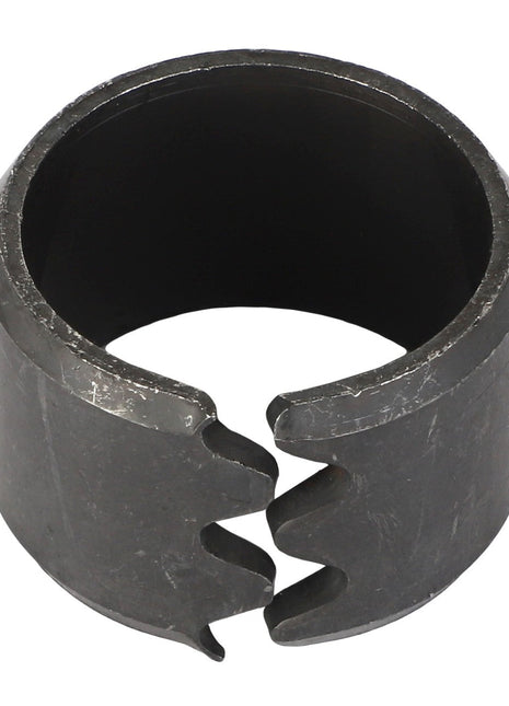 Introducing the AGCO Tension Bushing - Acp0015600, a cylindrical metal bushing with a split and textured surface, designed with two interlocking notches at the opening.