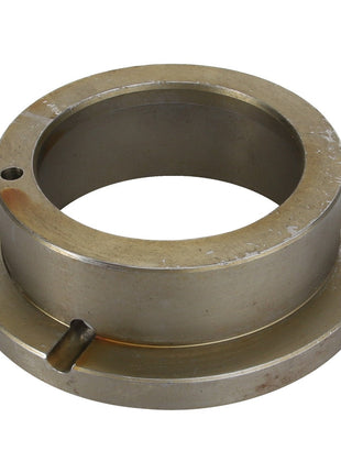 The AGCO | Bush - Acp0330690 is a circular metal mechanical component featuring a central hole, flanged edges, and two notches. It shows slight wear and tarnish on its surface.